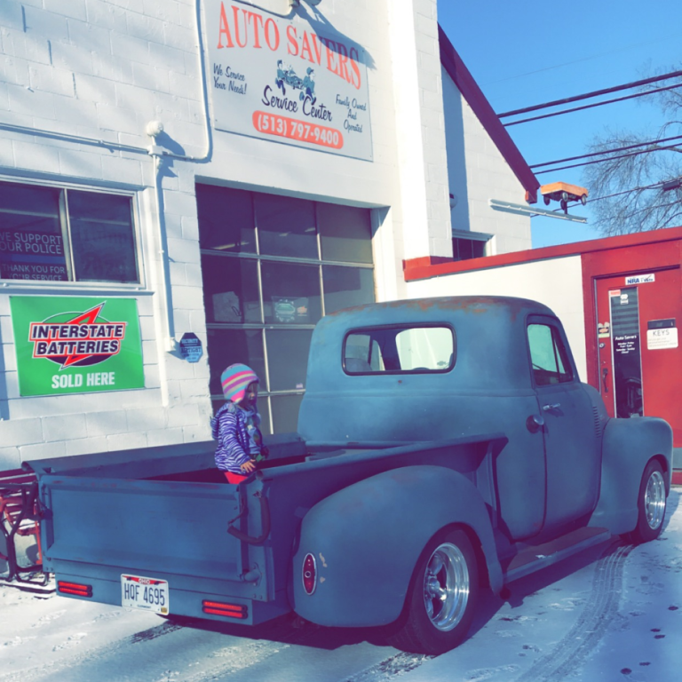 A classic pickup truck parked outside the Auto Savers shop on Center Street in New Richmond, Ohio, on a snowy day